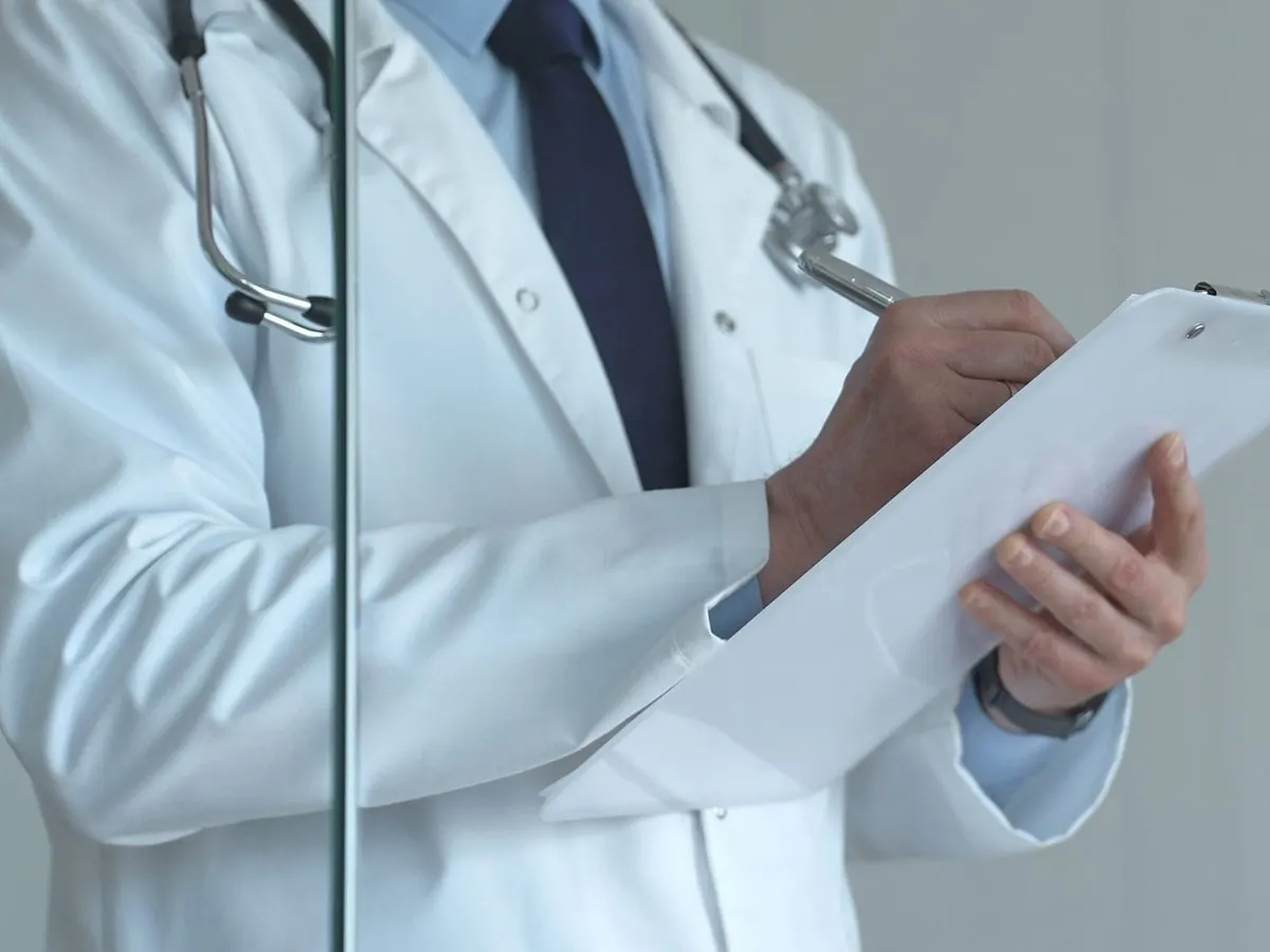 Stock photograph of a model: a doctor in a white coat and stethoscope writing on a clipboard