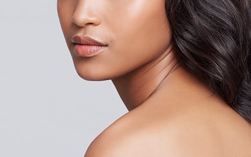 Stock photograph of a model: a woman with long dark hair in profile, her bare shoulder and clear, glowing skin