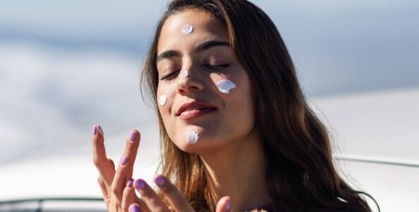 Stock photograph of a model: a woman applying sunscreen to her cheek on a snowy mountain