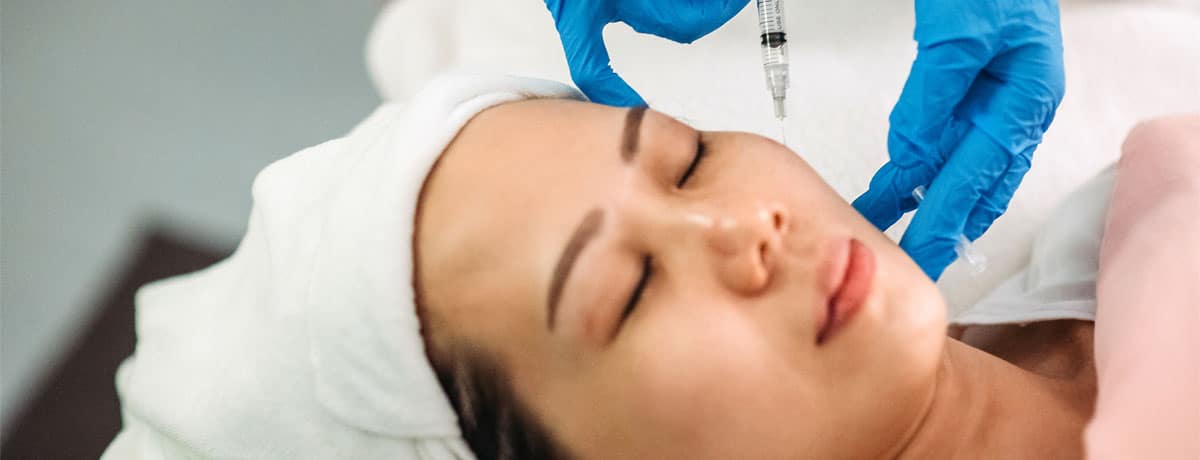 Asian chinese female receiving injection on the face at facial beauty salon