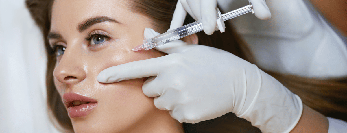 Young woman undergoing dermal filler treatment in cheek 